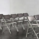 Rows of grey padded folding chairs set up in hall.