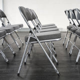 Side profile of rows of grey padded folding chairs in hall.