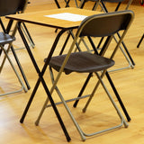 Rows of wooden folding exam desks and folding chairs set up in a hall ready for exams.