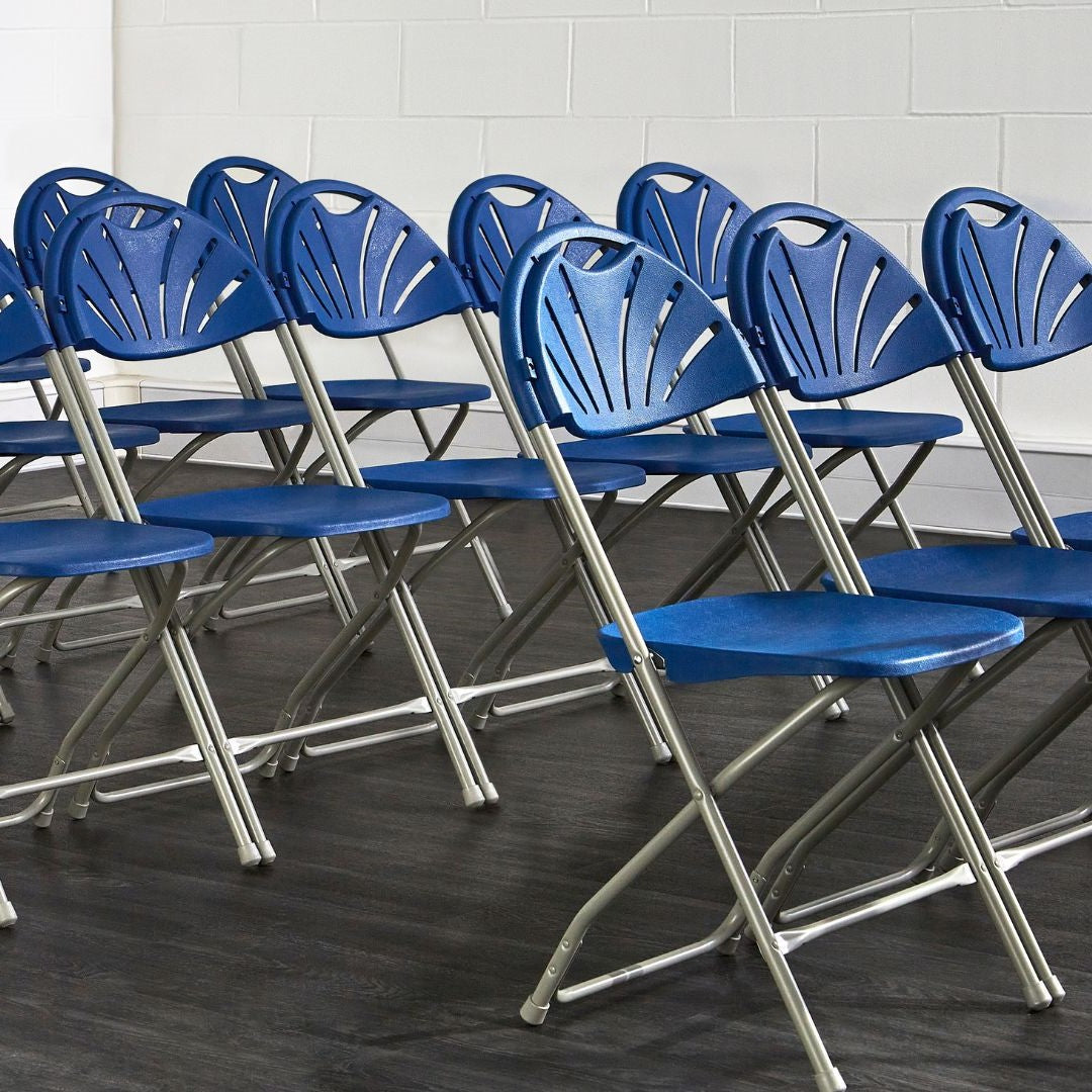 Rows of blue fan back plastic folding chairs in a hall.