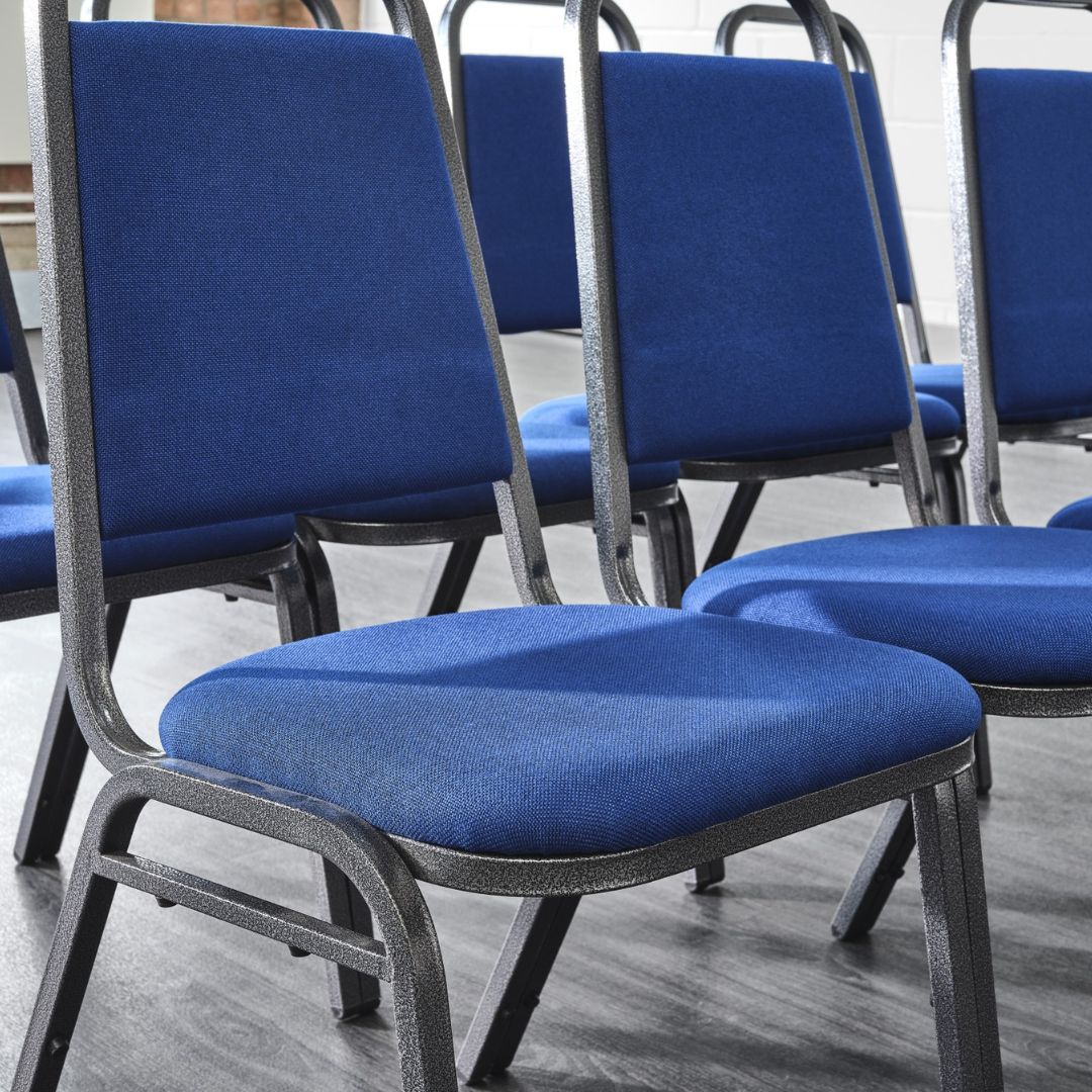 Rows of blue padded banqueting chairs in a room.