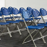 Rows of blue fan back plastic folding chairs in a hall.