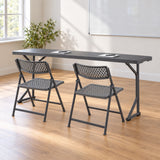 Zown M183 narrow folding table with two Shark Grey Aran folding chairs in a training room.
