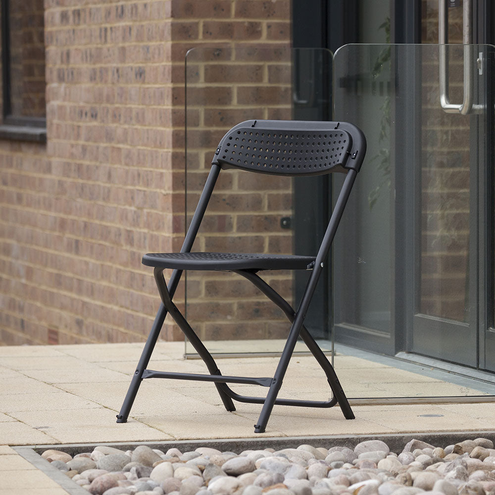 Black BigClassic Plastic Folding Chair outside modern building.