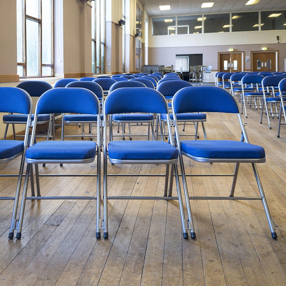 Rows of blue Comfort Deluxe padded folding chairs in community hall.