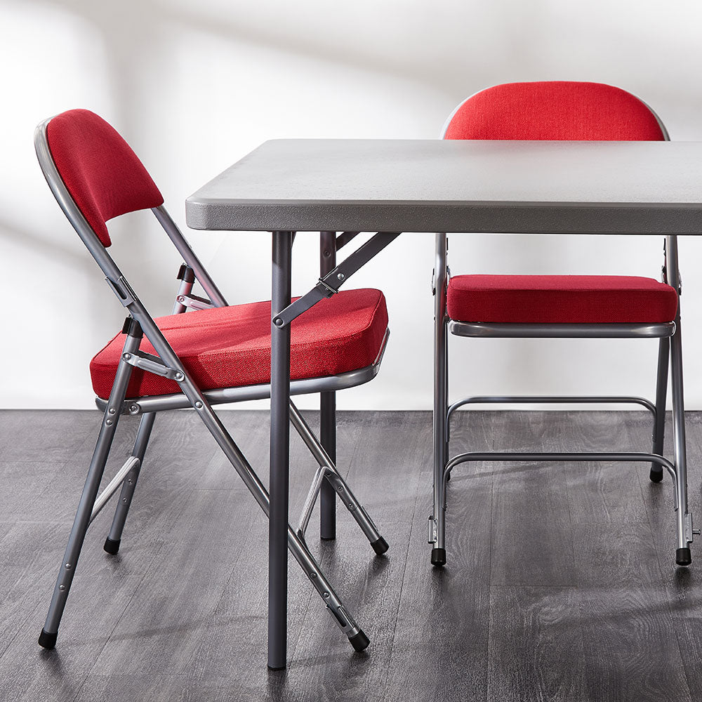 Red Comfort Deluxe padded folding chair around a grey folding table.