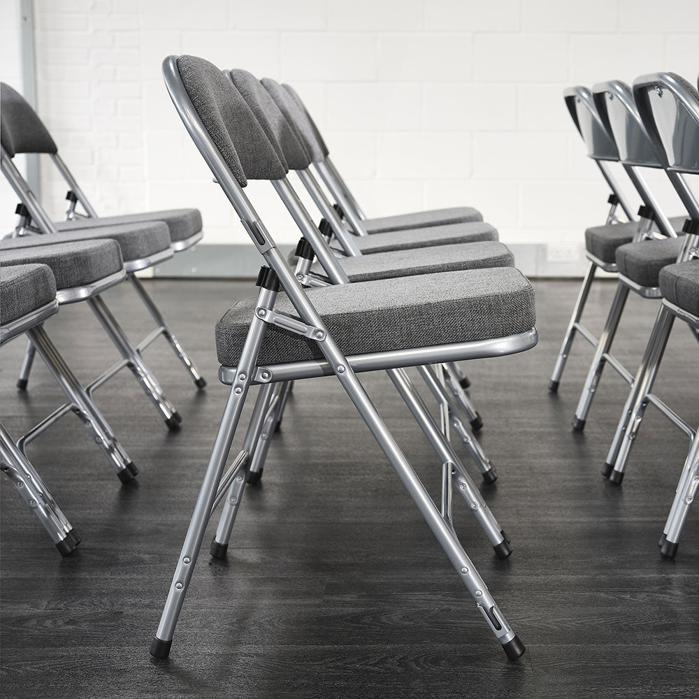 Side profile of rows of grey padded folding chairs in hall.