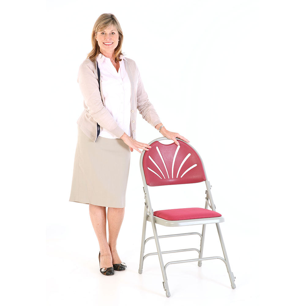 Model leaning on red padded folding chair.